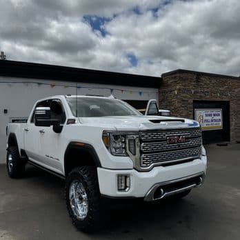 Clean lifted white GMC Denali truck outside the HeadLampChamp shop