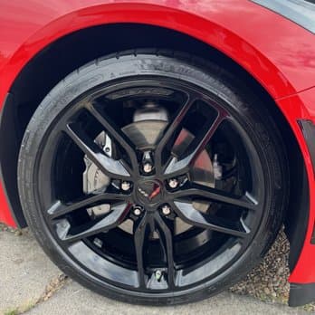 Detailed black wheel and brake caliper on a red Corvette